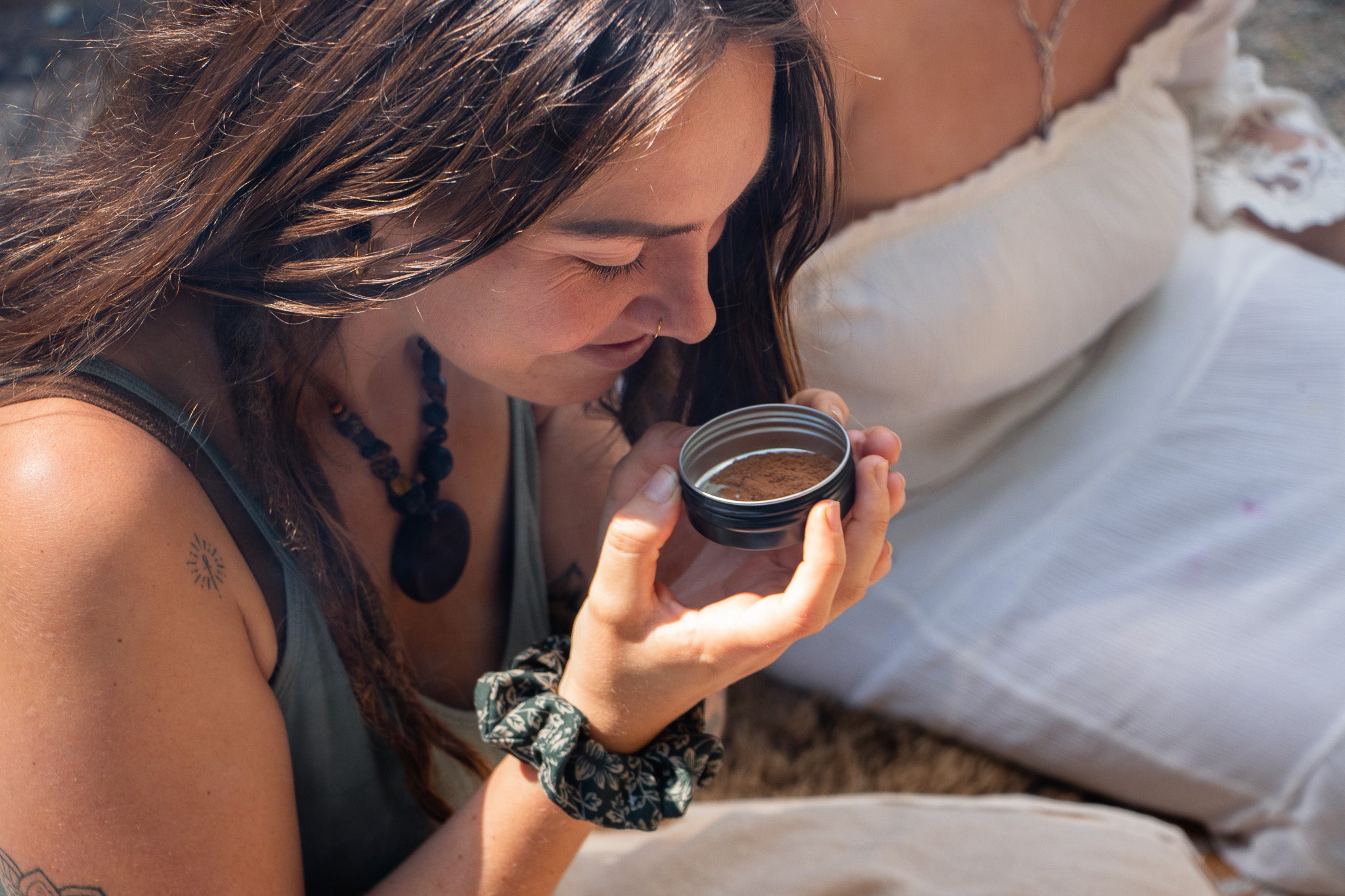 Woman holding a small container outdoors, smelling the ingredients 